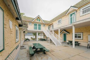 A building with a covered patio area, outdoor seating, and a staircase leading to an upper level.