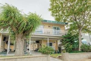 A two-story building with a balcony, named 'Green Gables Beach Resort,' surrounded by trees and a concrete walkway.
