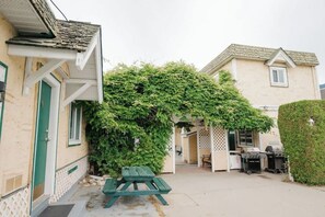A residential area with a green picnic table, a covered patio, and a barbecue grill.