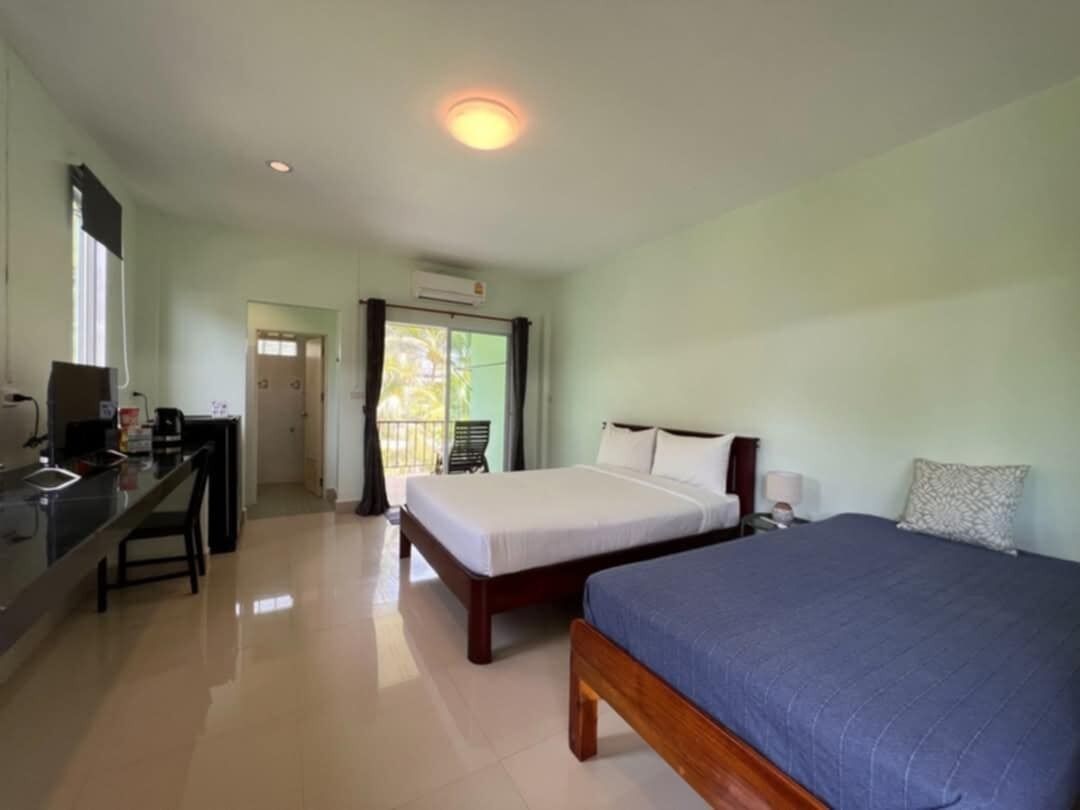 A hotel room with two beds, a desk, a chair, and a window.