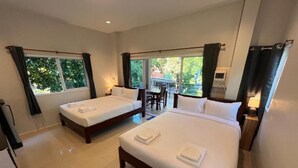 A hotel room with two beds, a small table, and a view of the outdoors. - Naisang Hostel (Chumphon)
