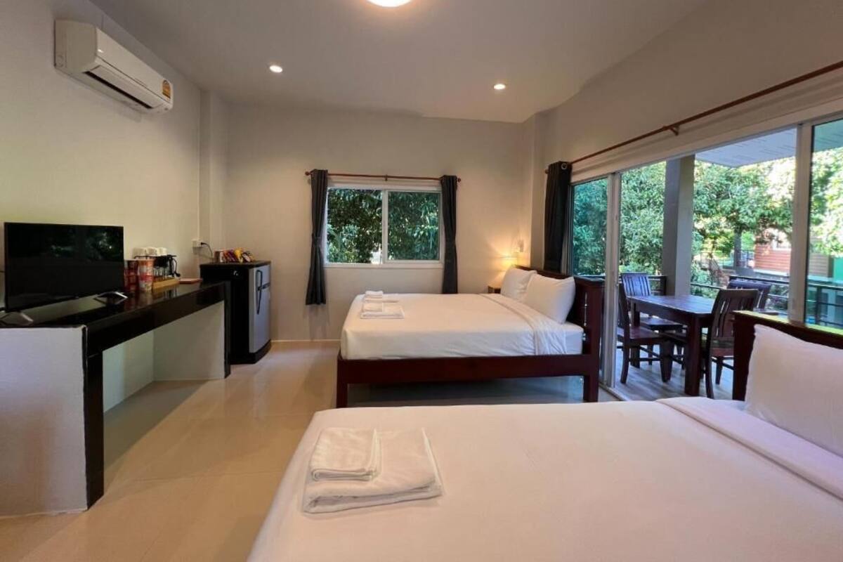 Habitación de hotel con cama, escritorio con televisor, una mesita y balcón con mesa y sillas.