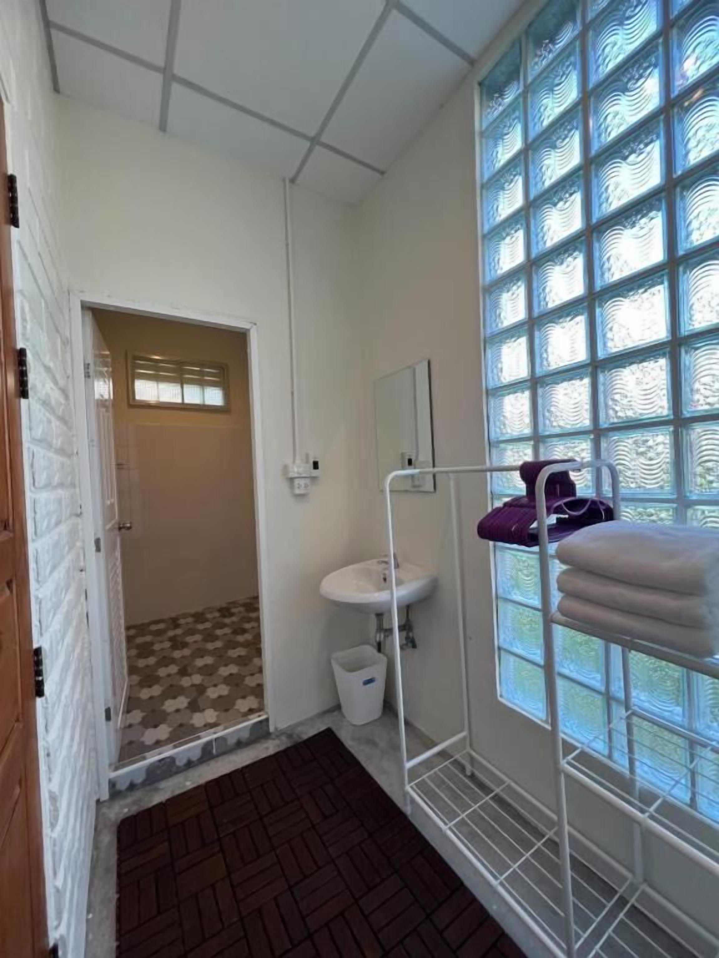 A bathroom with a sink, mirror, and window with patterned glass.