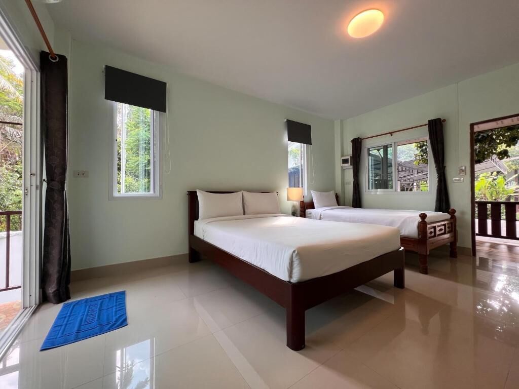 A bedroom with two beds, a large window, and a balcony.