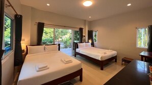 A hotel room with two beds, a desk, and a view of greenery outside. - Naisang Hostel (Chumphon)
