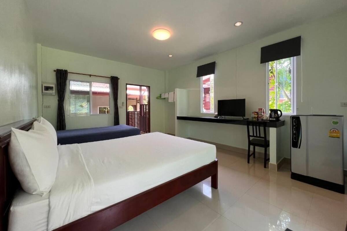 Una habitación con cama, escritorio, refrigerador y ventana.