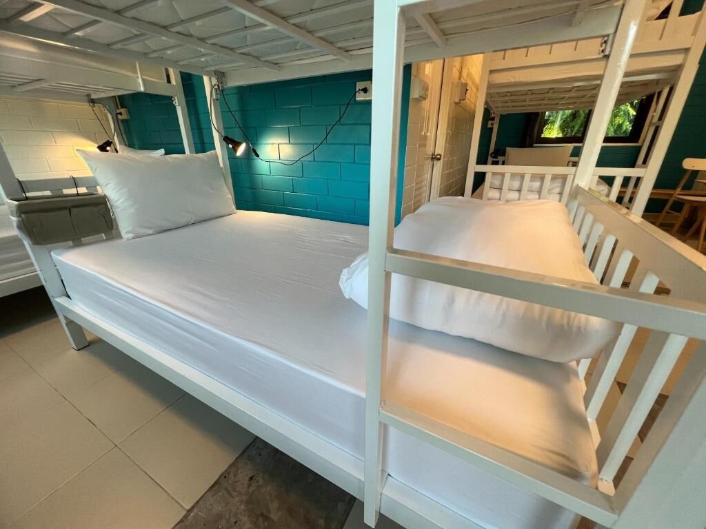 A bunk bed with white bedding, a teal accent wall, and a white ceiling.