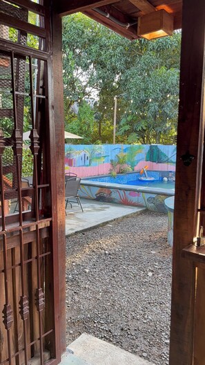 Un espace extérieur doté d’une piscine, d’une fresque murale et d’un portail en bois.