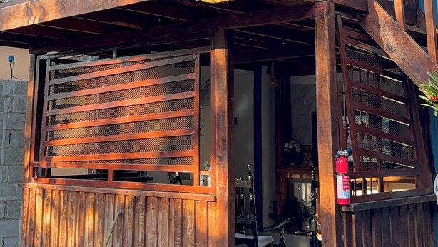 A wooden two-story building with a balcony, a covered entrance, and a fire extinguisher. - Fresh country air, tranquility, pool, and BBQ—pets welcome. (Bonao)