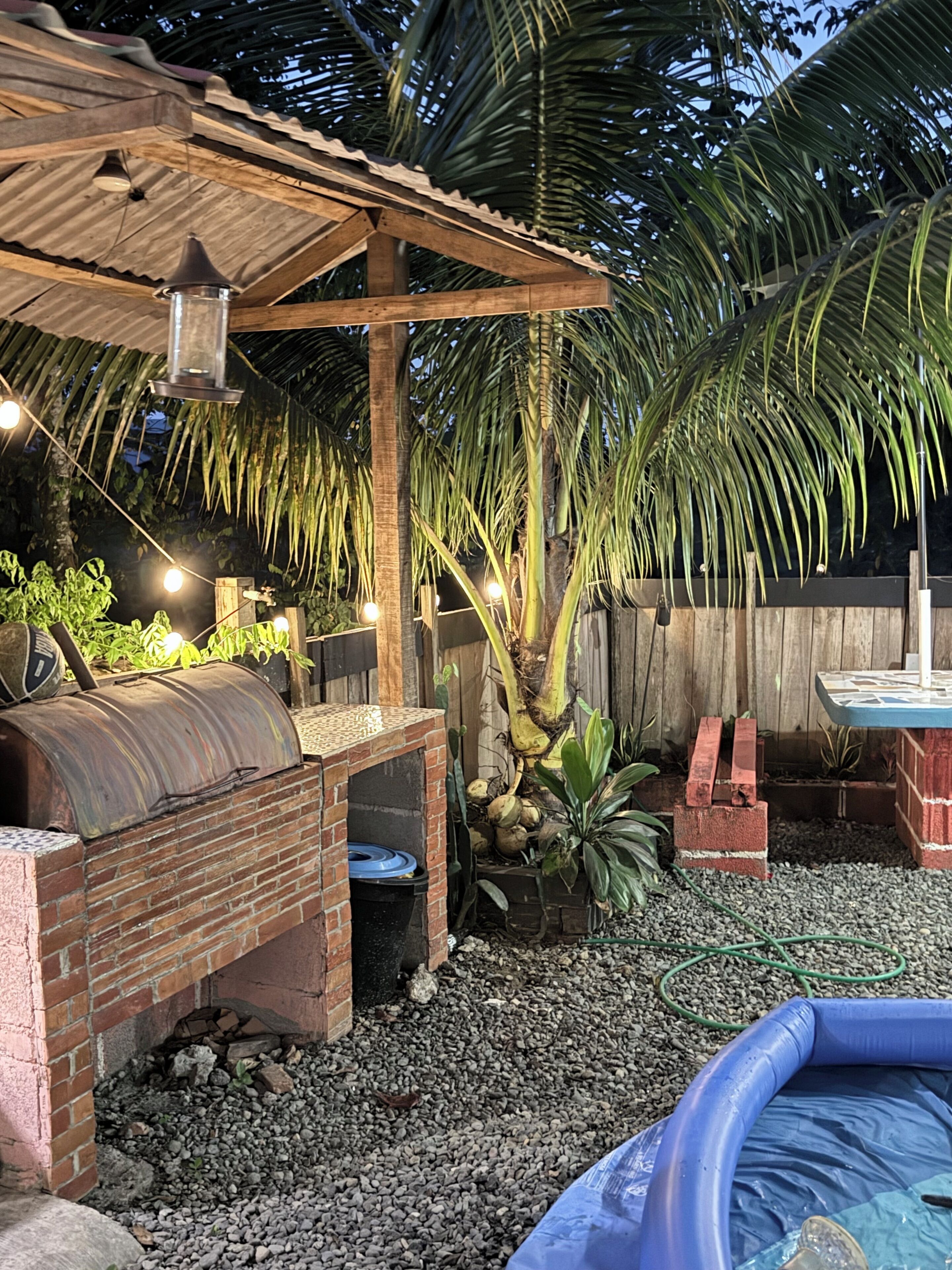 A backyard with a barbecue area, a small pool, and a wooden pergola.
