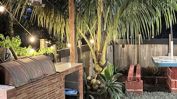 A backyard with a barbecue area, a small pool, and a wooden pergola.