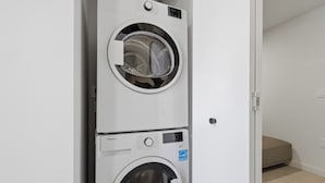 A stacked washer and dryer unit in a room with a door leading to another space. - AEA - 121 NE 5th St Miami (Miami)
