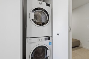 A stacked washer and dryer unit in a room with a door leading to another space. - AEA - 121 NE 5th St Miami (Miami)