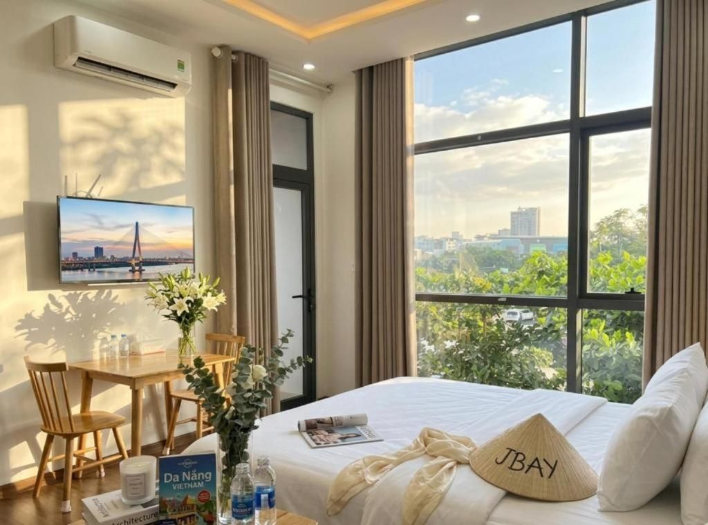 A hotel room with a bed, a desk, a chair, a TV, and a window with a city view.