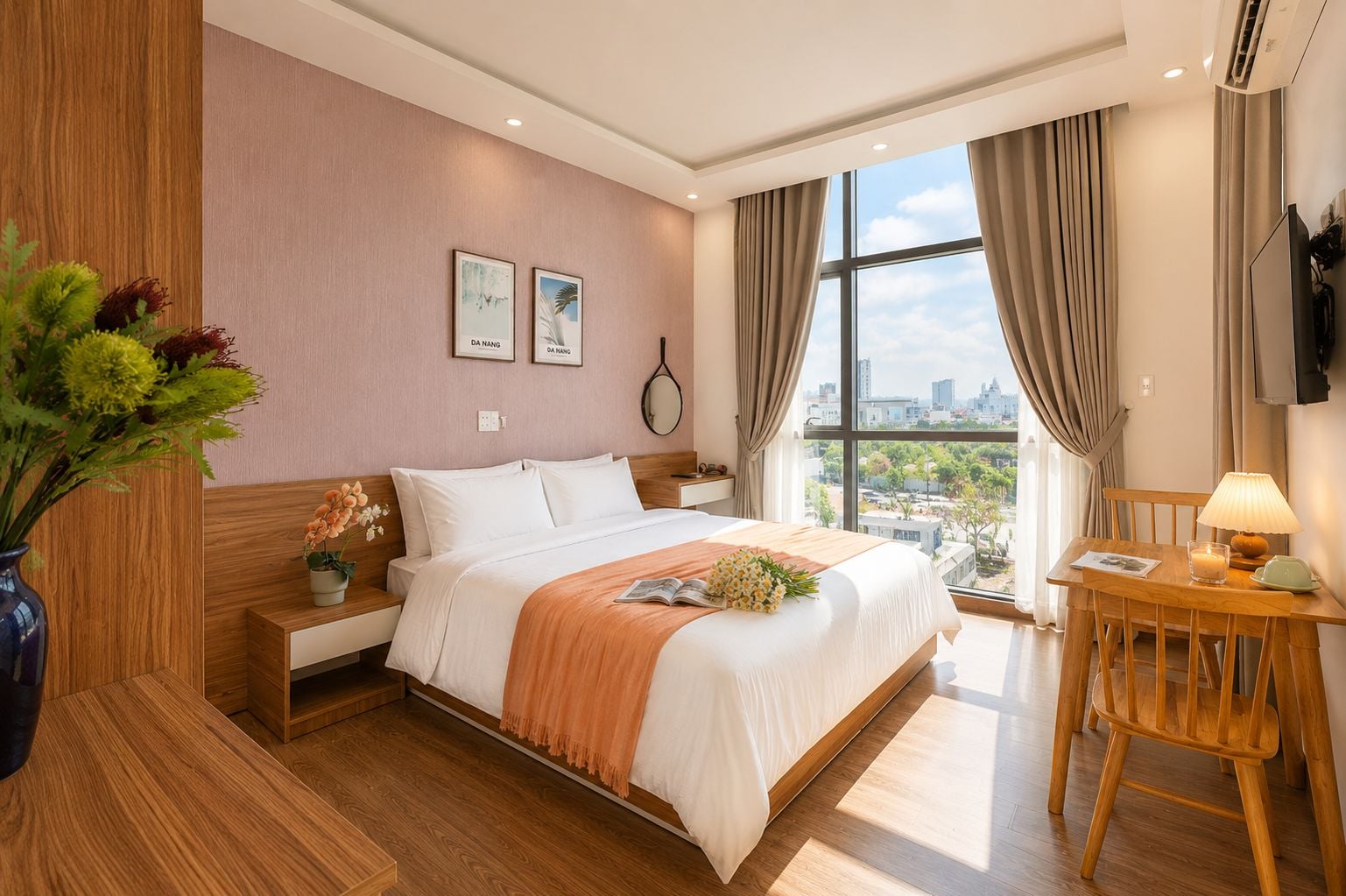 A hotel room with a bed, bedside table, lamp, and a view of the city through large windows.