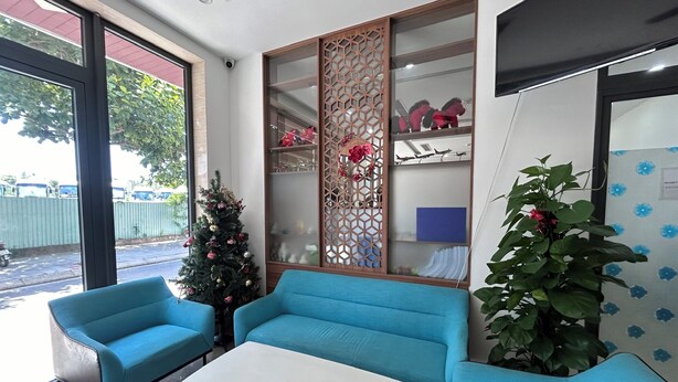 A reception area with a Christmas tree, blue sofas, a white table, and a large window. - JBAY Riverfront Boutique Hotel (Da Nang)