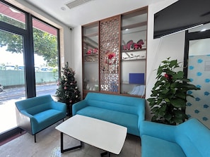 A reception area with a Christmas tree, blue sofas, a white table, and a large window. - JBAY Riverfront Boutique Hotel (Da Nang)
