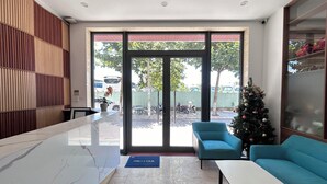 A reception area with a marble counter, two sofas, a Christmas tree, and a view of the street outside. - JBAY Riverfront Boutique Hotel (Da Nang)
