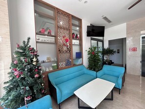 Um saguão com árvore de Natal, sofás azuis e uma mesa branca.