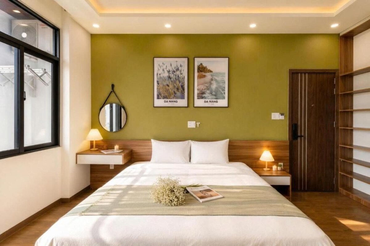 A hotel room with a bed, two bedside lamps, a mirror, and two framed pictures on the wall.