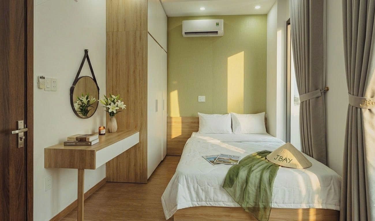 Una camera d'albergo con un letto, un comodino, uno specchio e un condizionatore d'aria a parete.