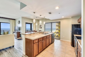 A modern kitchen with a large island, built-in appliances, and a view to the outside.