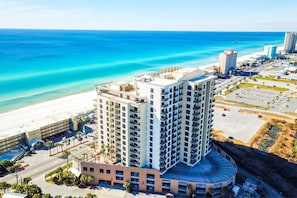 A high-rise hotel with multiple floors, a beach view, and a parking area.