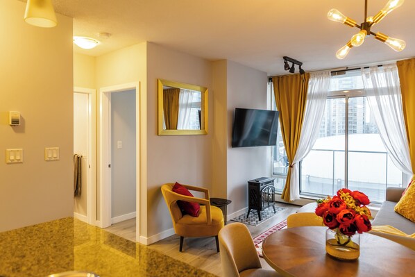 A modern living room with a flat-screen TV, a dining table, and a sofa. - Rogers Arena, BC Place - Prime Location (Vancouver)