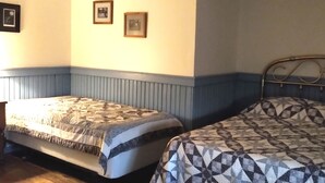 Een slaapkamer met twee bedden, houten vloeren en een muur met drie ingelijste foto's.