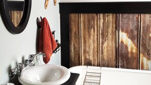 Een badkamer met een witte wastafel, een spiegel en een raam met houten kader.
