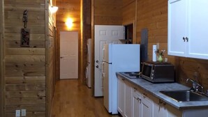 Un interior de madera con área de cocina, que incluye un refrigerador, un microondas y un lavamanos.