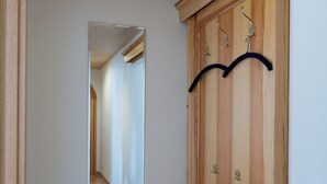 En hall med en träbänk, en spegel och en garderob med krokar.