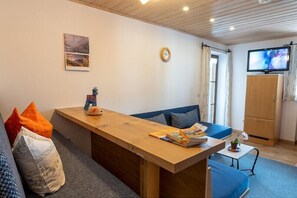 A cozy living room with a sofa, a wooden table, a television, and a cabinet. - Apartment no. 3, 1-2 persons, 39 sqm, balcony and terrace, TV, WLAN (Ramsau bei Berchtesgaden)