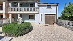 Ein zweistöckiges Gebäude mit Balkon, Statue und Garage.