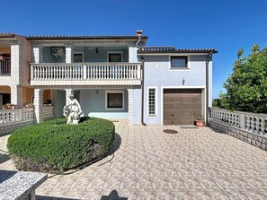 Ein zweistöckiges Gebäude mit Balkon, Statue und Garage.