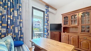 A room with a sofa, a wooden table, a television, and wooden cabinets. - Apartment Ivo by Interhome (Pula/Banjole)