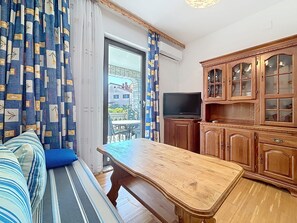 A room with a sofa, a wooden table, a television, and wooden cabinets. - Apartment Ivo by Interhome (Pula/Banjole)