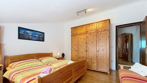 Ein Schlafzimmer mit einem hölzernen Bett, einem Kleiderschrank, einem Spiegel und einem Gemälde an der Wand.