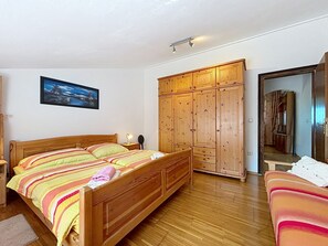 Ein Schlafzimmer mit einem hölzernen Bett, einem Kleiderschrank, einem Spiegel und einem Gemälde an der Wand.