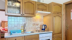 Eine Küche mit Holzausstattung, einem Edelstahl-Spülbecken, einem Wasserkocher und einem eingebauten Backofen.