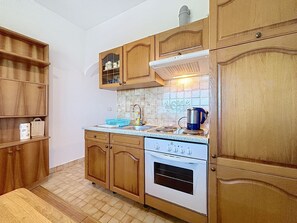 A kitchen with wooden cabinets, a stove, and a tiled backsplash. - Apartment Ivo by Interhome (Pula/Banjole)