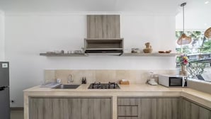 Una cocina moderna con estufa integrada, microondas y pileta, muebles de madera y una ventana con vista.