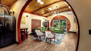 Een interieur met een houten plafond, een eethoek met stoelen en een tafel, en een groene bank.