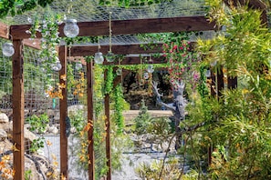 Un jardin agrémenté d’une pergola en bois, de pots en verre suspendus et de différentes plantes.