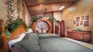 Een slaapkamer met een groot bed, een houten dressoir, een decoratieve boom aan de muur en een ronde houten deur.
