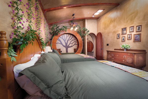 Un dormitorio con una cama grande, un aparador de madera, un adorno de árbol en la pared y una puerta de madera circular.