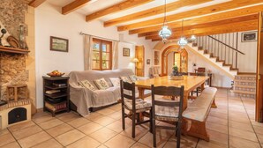 Una sala de estar acogedora con chimenea, una mesa de comedor y una escalera que lleva a un nivel superior.