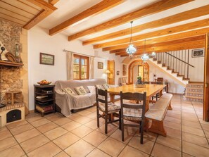 Ein gemütliches Wohnzimmer mit Kamin, einem Esstisch und einer Treppe, die in eine obere Etage führt.