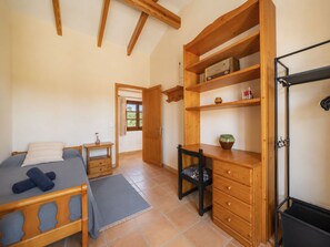 Ein Schlafzimmer mit Bett, Schreibtisch, Stuhl, Kleiderschrank und Heizkörper.