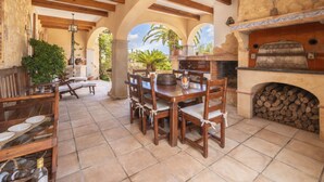 Un patio al aire libre con muebles de madera, una chimenea de piedra y plantas en macetas.